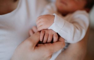 A young woman with her new baby boy or girl in arms.